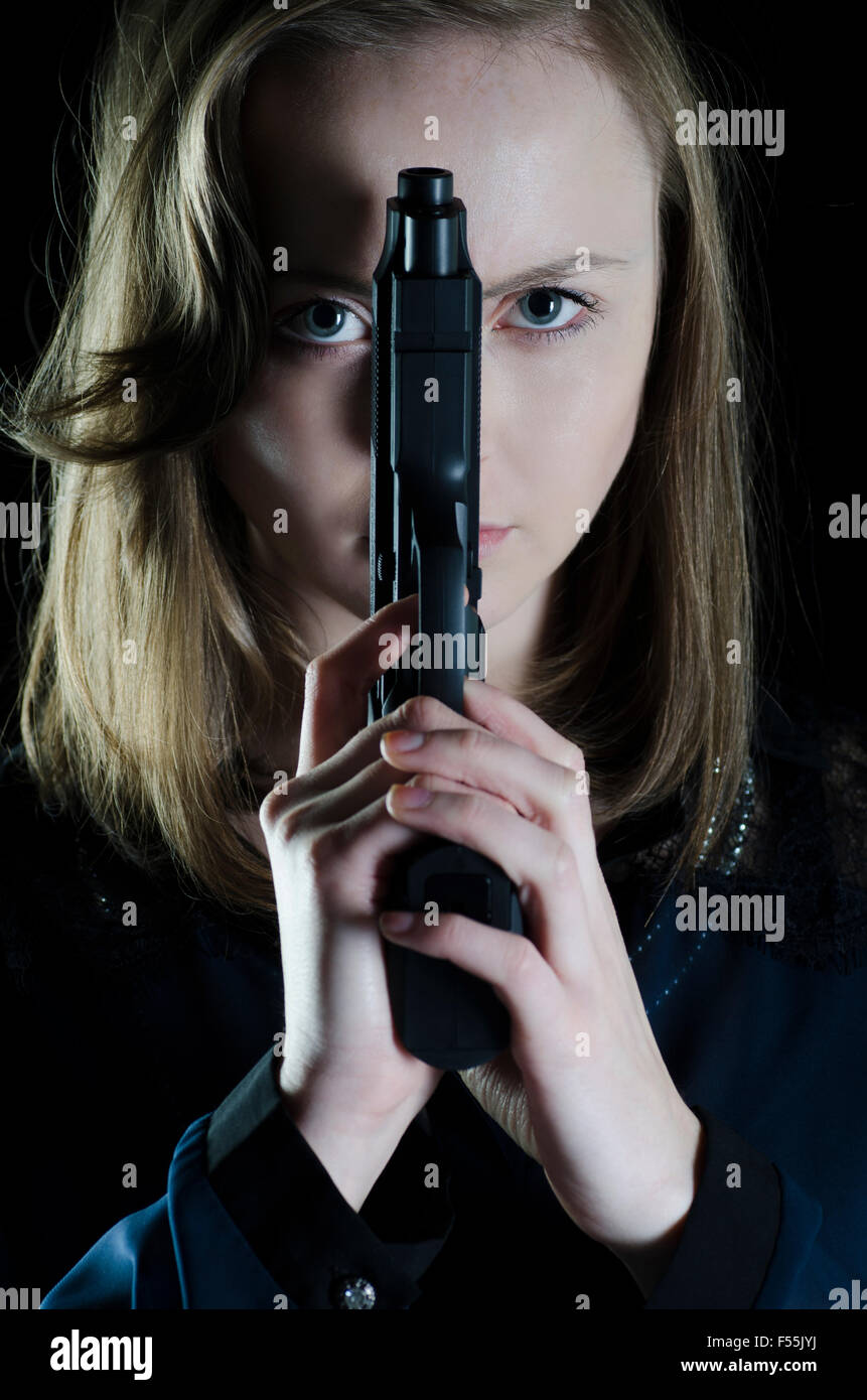Serious young woman armed holding a gun Stock Photo