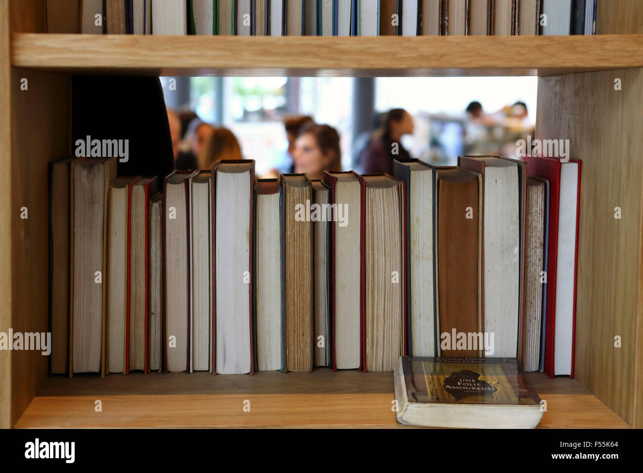 books in a bookshelf with out of focus people in the background Stock Photo