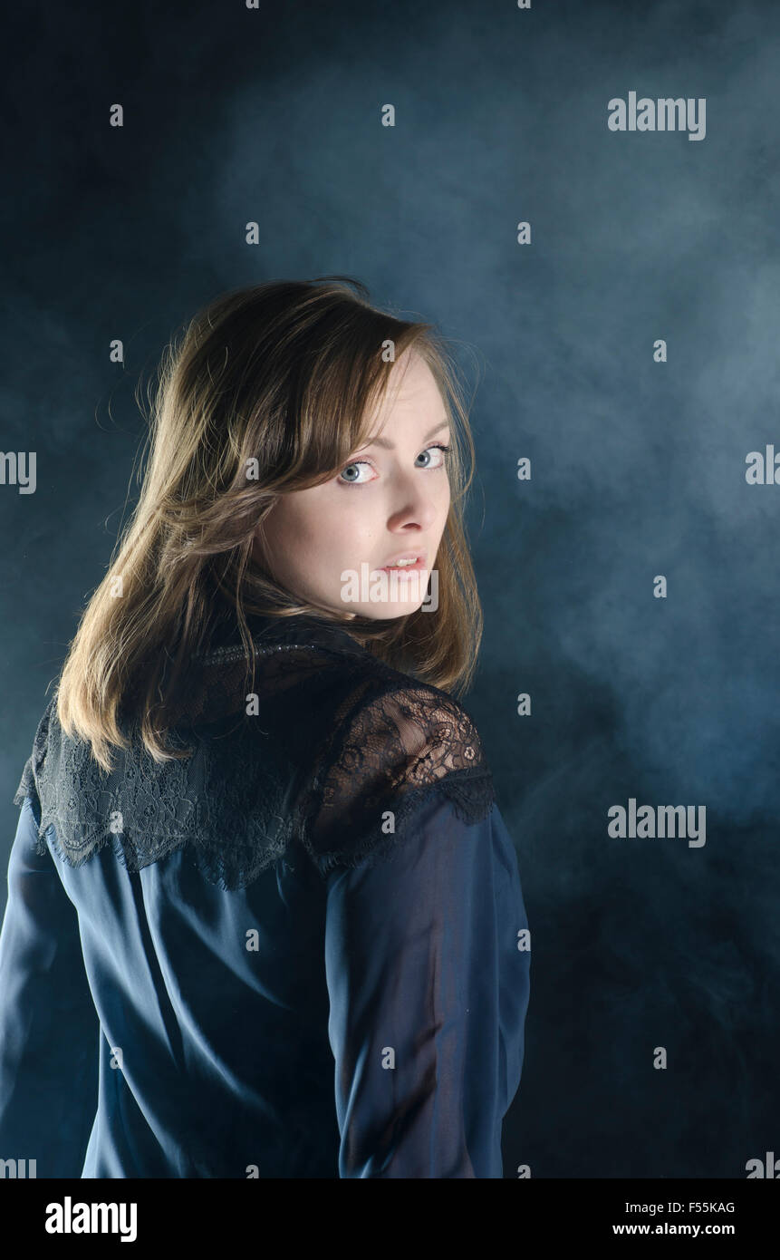 Scared young woman looking over shoulder in the dark Stock Photo