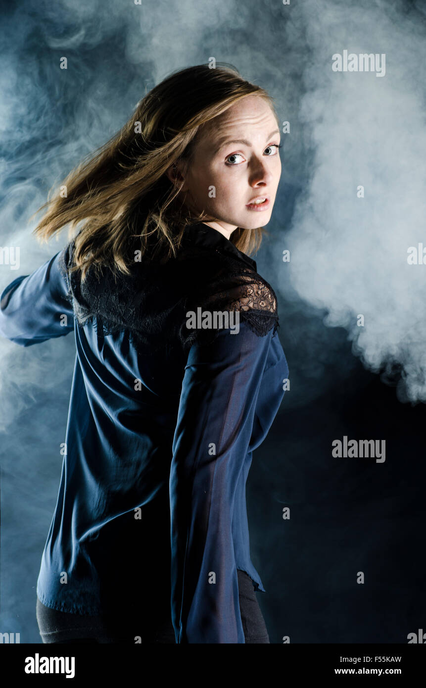 Scared young woman running away in the dark looking over shoulder Stock Photo