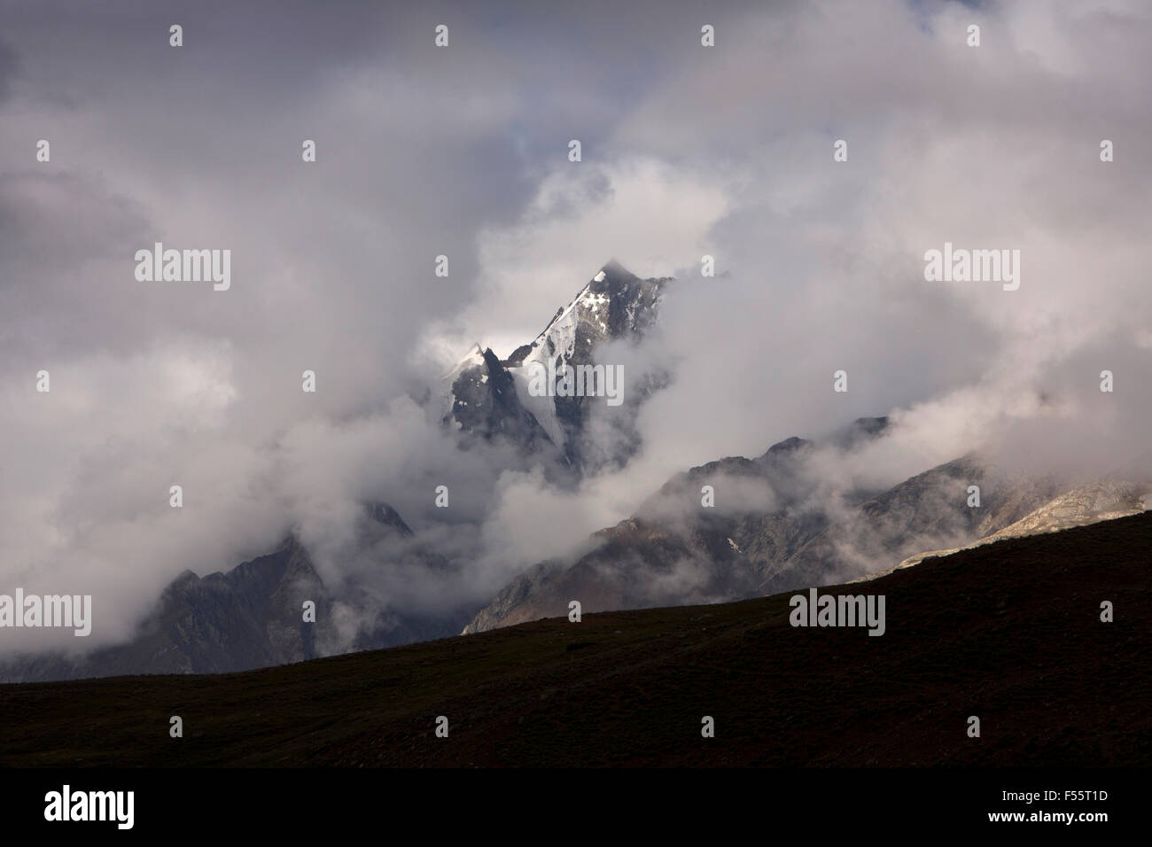 India, Himachal Pradesh, Spiti, Chandra Taal, Snow capped Bhaga Mountains glimpsed through early morning cloud Stock Photo