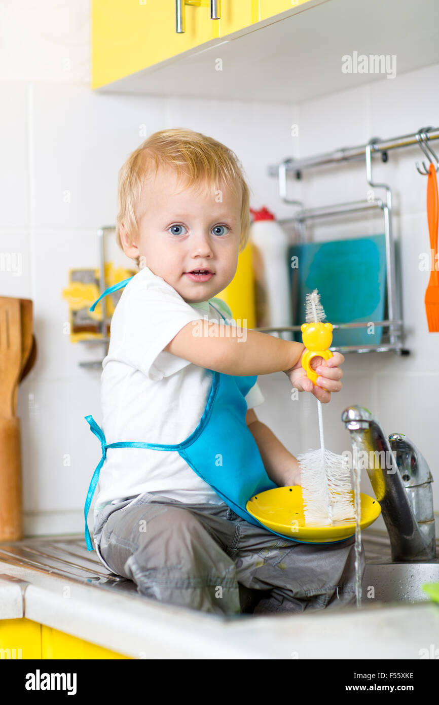 Child boy washing dishes and having fun in the kitchen Stock Photo