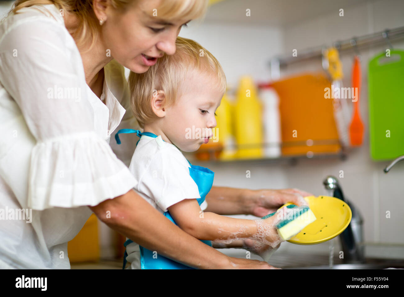 Mother teaches her little child son to wash-up Stock Photo