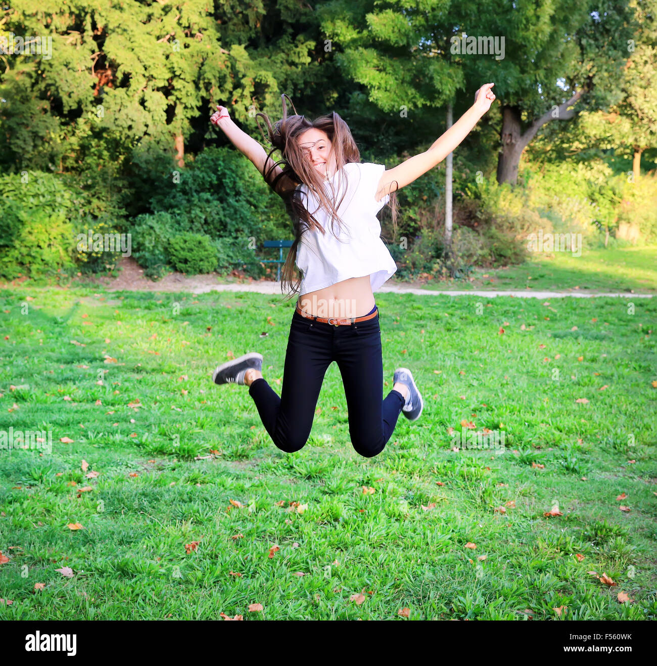 Beautiful happy young teen girl jumping high in the park Stock Photo