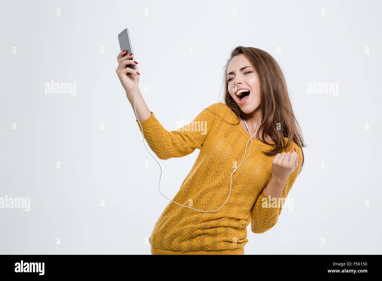 Portrait of a happy woman listening music in headphones and dancing ...