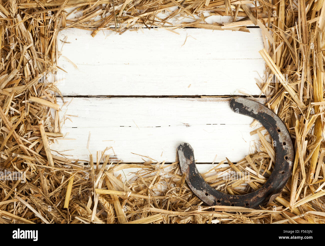 Decorative straw border and old horseshoe on white painted wooden Stock