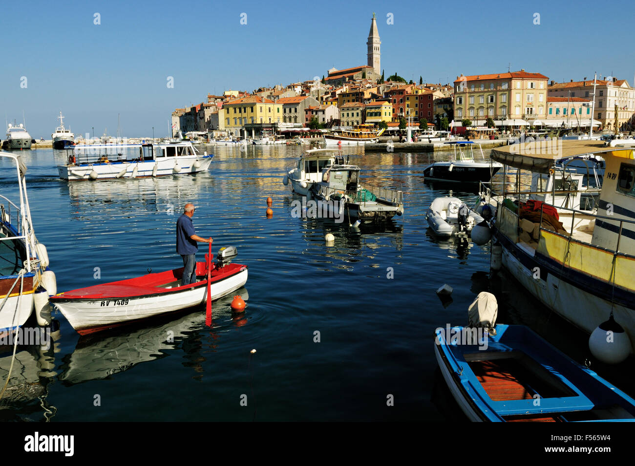 Man on a small red and white boat in the harbor of Rovinj, Istria, Croatia Stock Photo