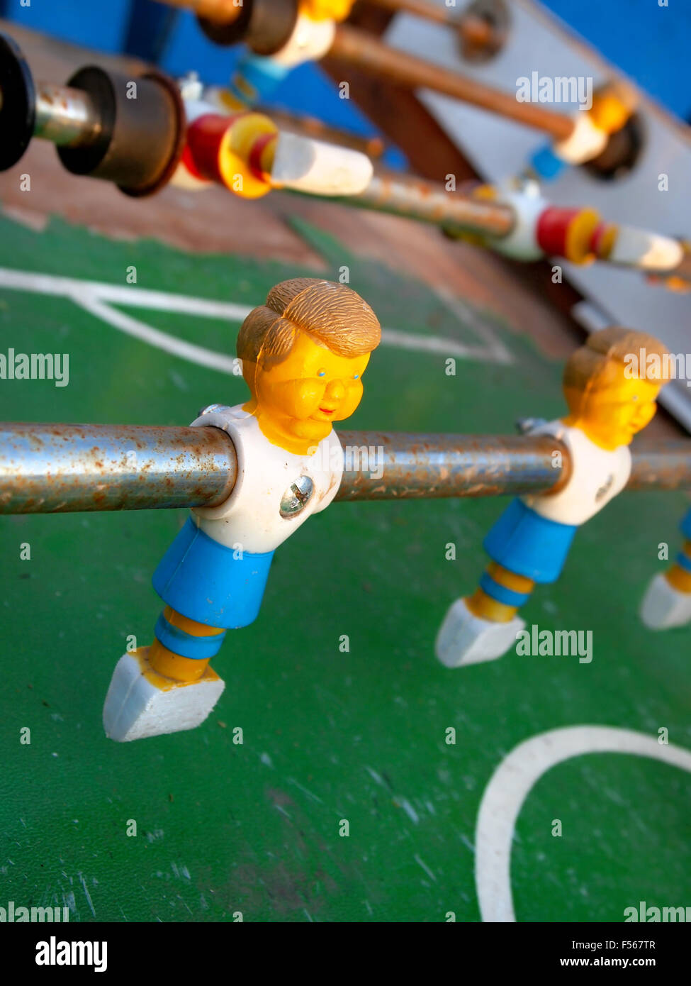 Closeup on a plastic foosball player on a control stick on a rusty old game table. Stock Photo