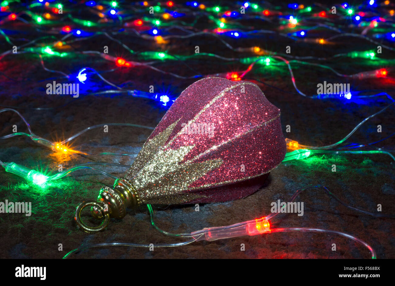 Toy rests upon festoon of the colour lights on dark background Stock Photo