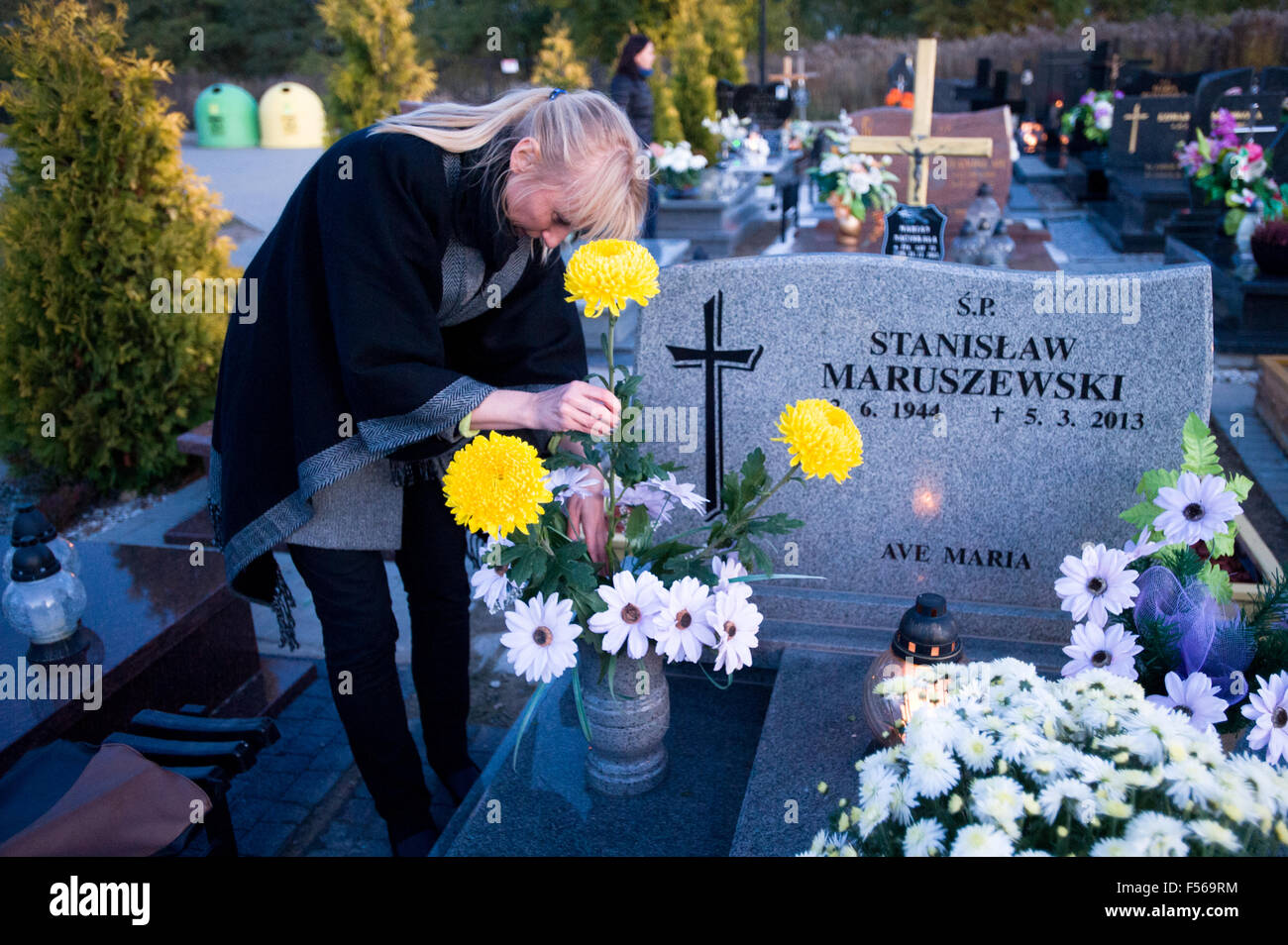 Wielun, Poland. 28th October, 2015. A woman makes flower arrangement on the grave as a part of preparations to celebrate catholic All Saint's Day on 1st of November. Stock Photo