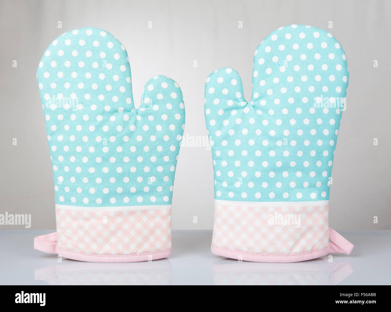 Dotted green oven gloves pair, kitchen mittens green pink fabric material white spotted and checkered cloth, safety gloves Stock Photo