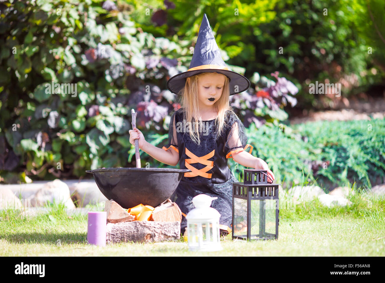 Adorable little girl in witch costume casting a spell on Halloween ...
