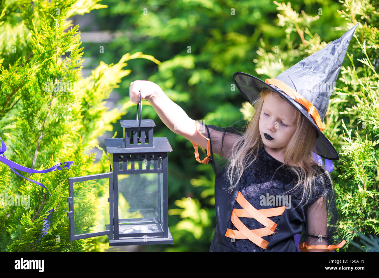 Adorable little girl wearing witch costume casting a spell on Halloween ...