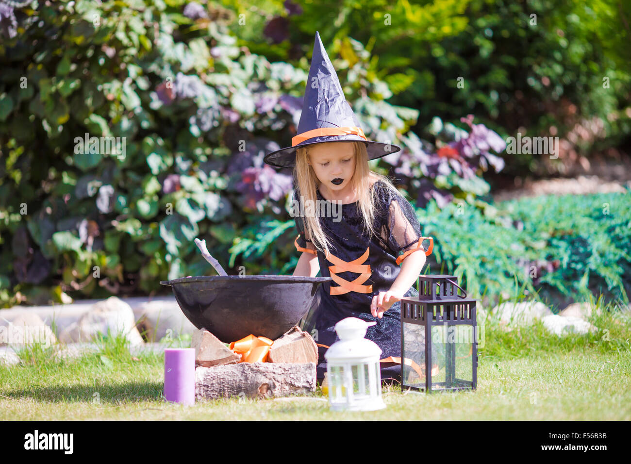 Adorable little girl wearing witch costume casting a spell on Halloween ...