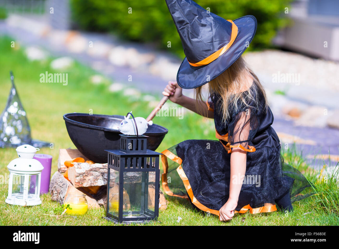 Adorable little girl wearing witch costume casting a spell on Halloween ...