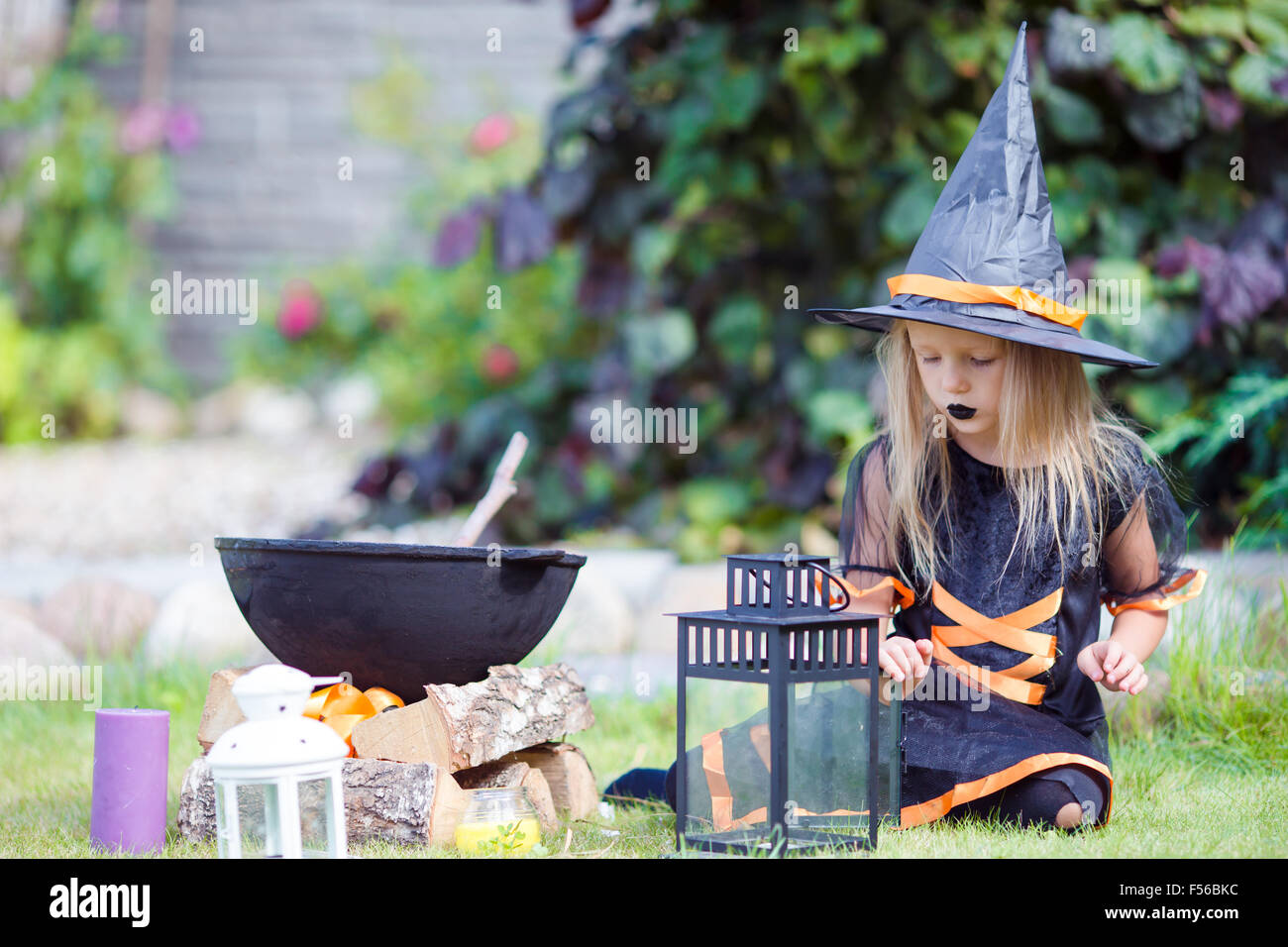 Adorable little girl wearing witch costume casting a spell on Halloween ...