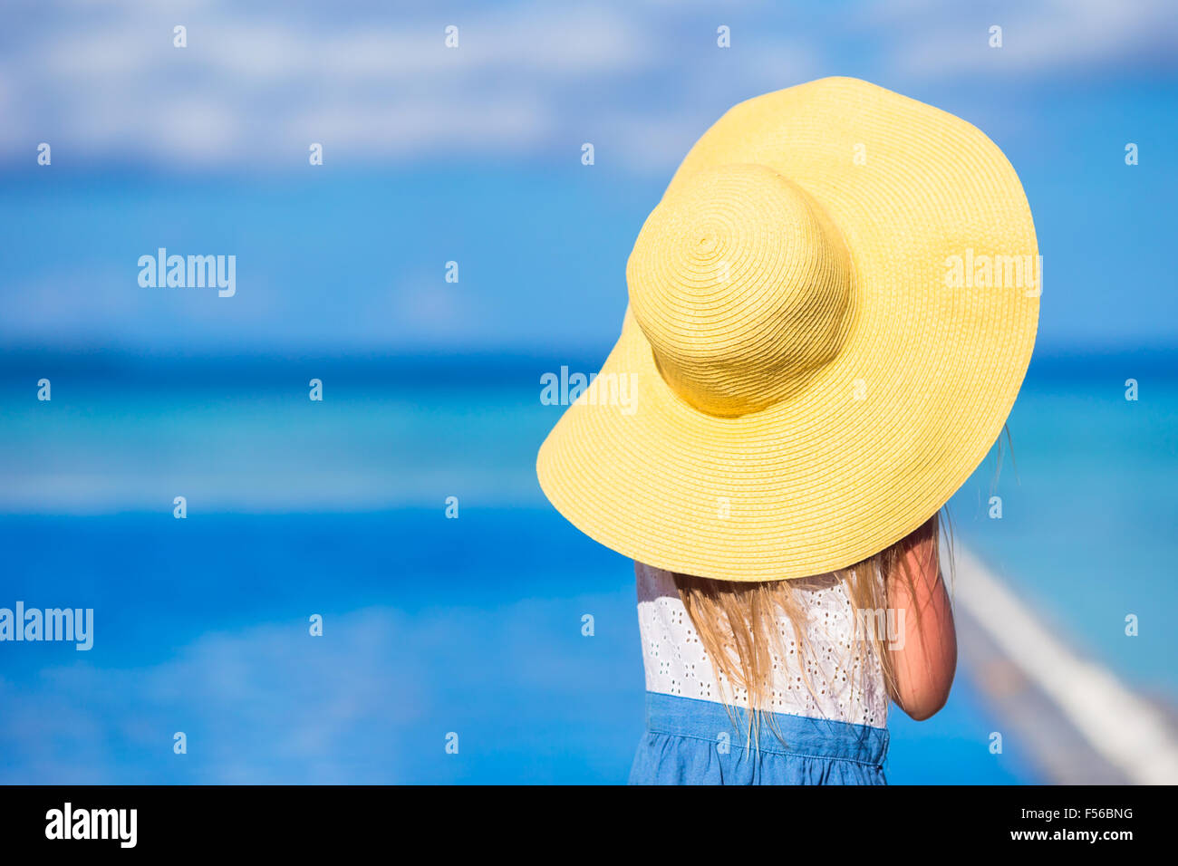Adorable happy little girl in big yellow hat on beach vacation Stock