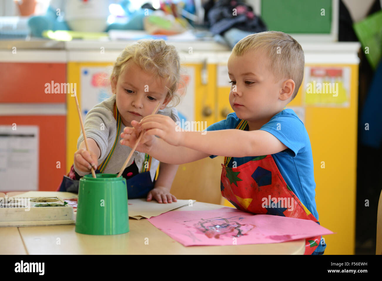 A little girl & boy painting at nursery school. Stock Photo