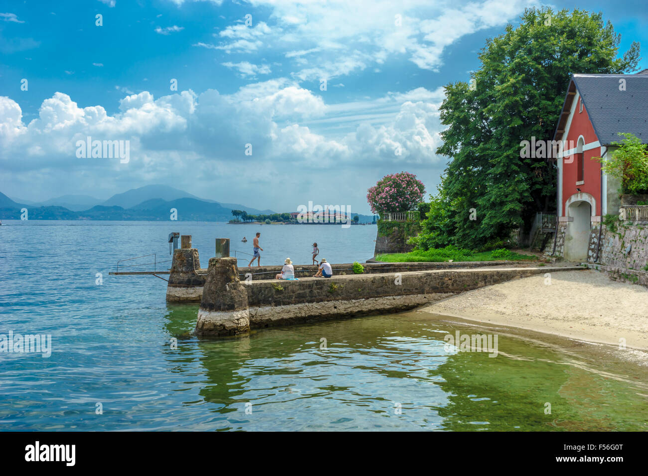 People rest and play on an old dock on Lake Maggiore in summer. Stock Photo