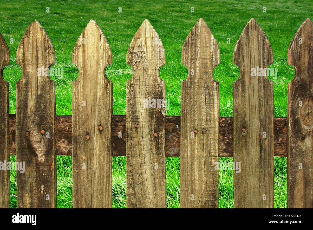 a field of lush green grass with a old wooden fence in foreground Stock Photo