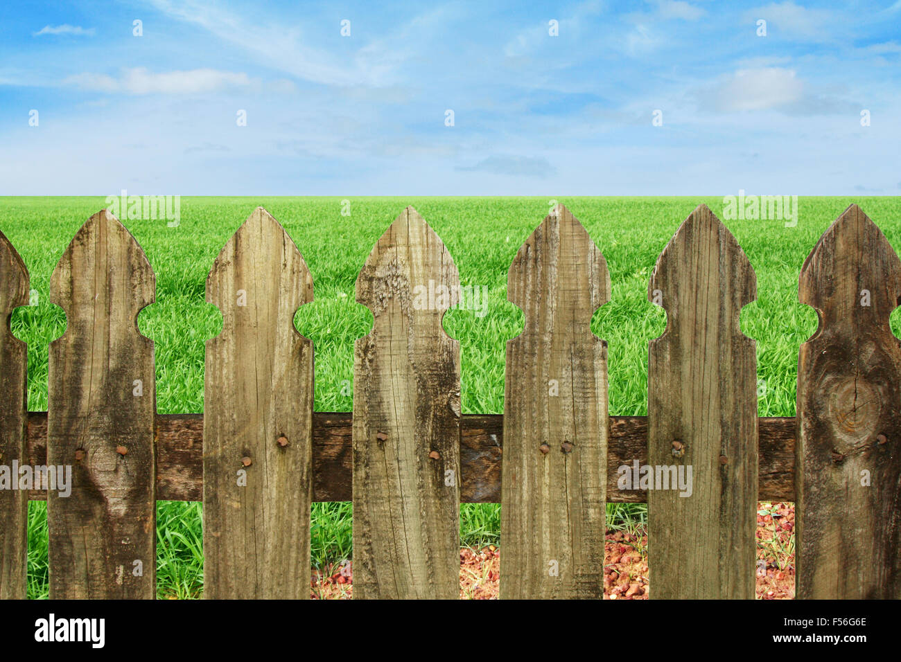 close up of an old fence with blue sky and green grass background Stock Photo