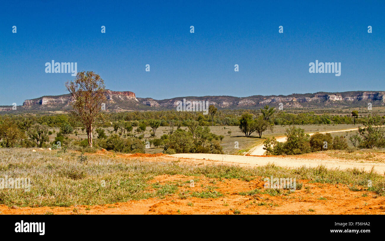 Panoramic landscape with winding road leading to Salvator Rosa National Park & Carnarvon Ranges rising into blue sky, outback Australia Stock Photo