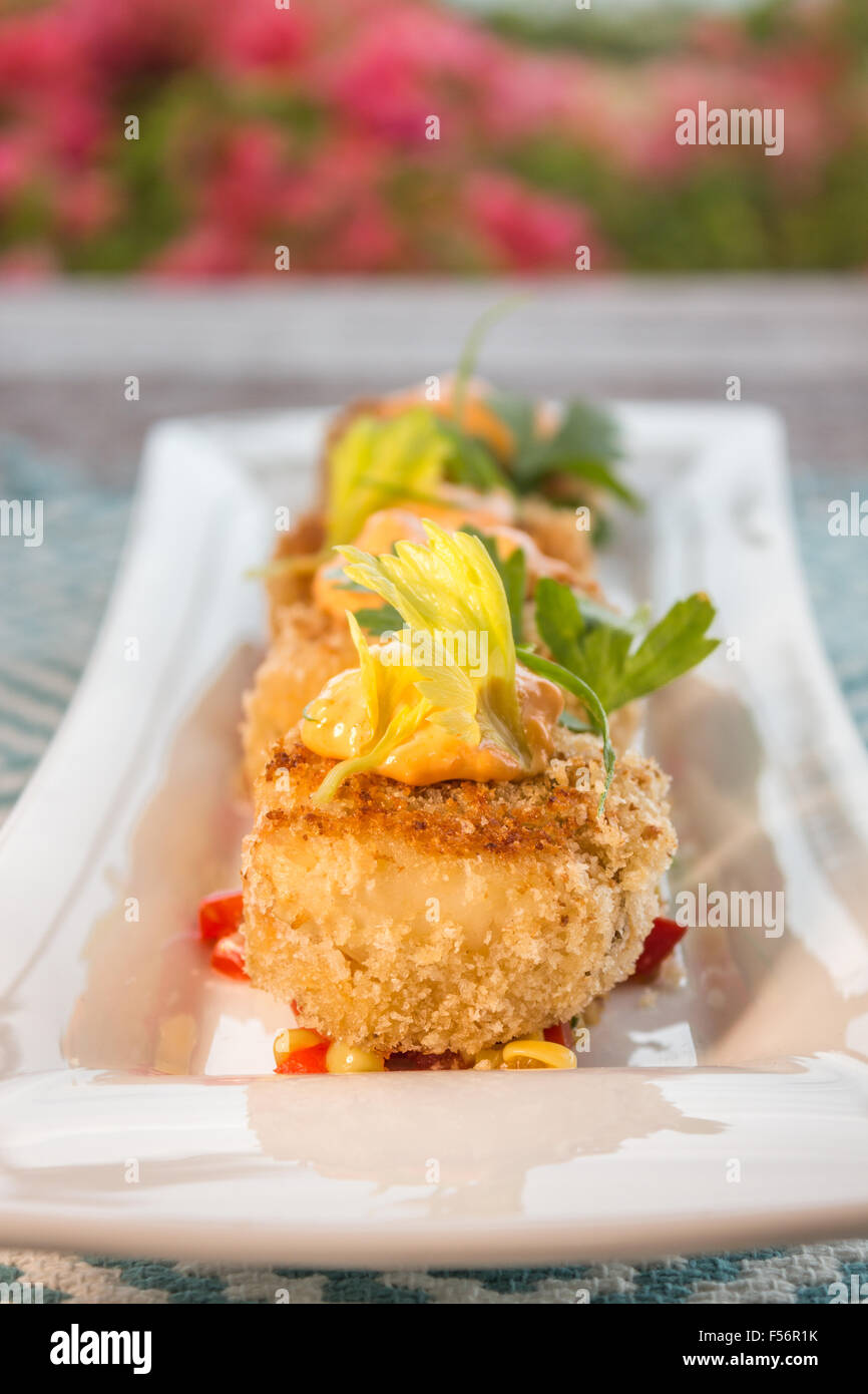Breaded crab cakes served on top of corn relish and topped with sauce Stock Photo