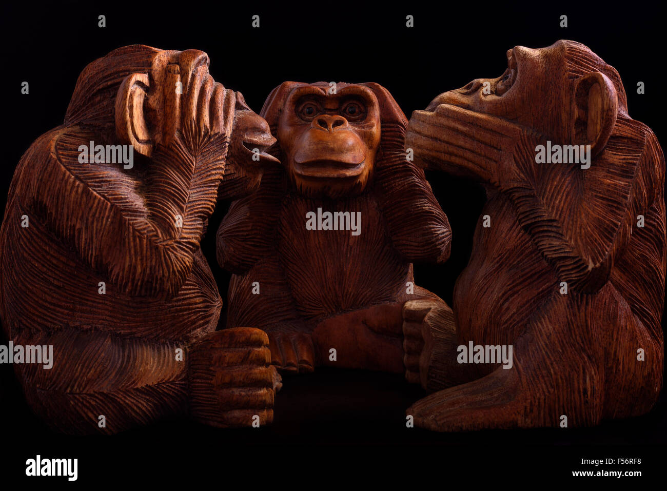 Three wise monkeys. Figurines of wood on a black background. Stock Photo