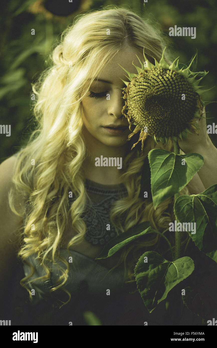 Beautiful young woman in a sunflower field at golden hour Stock Photo ...