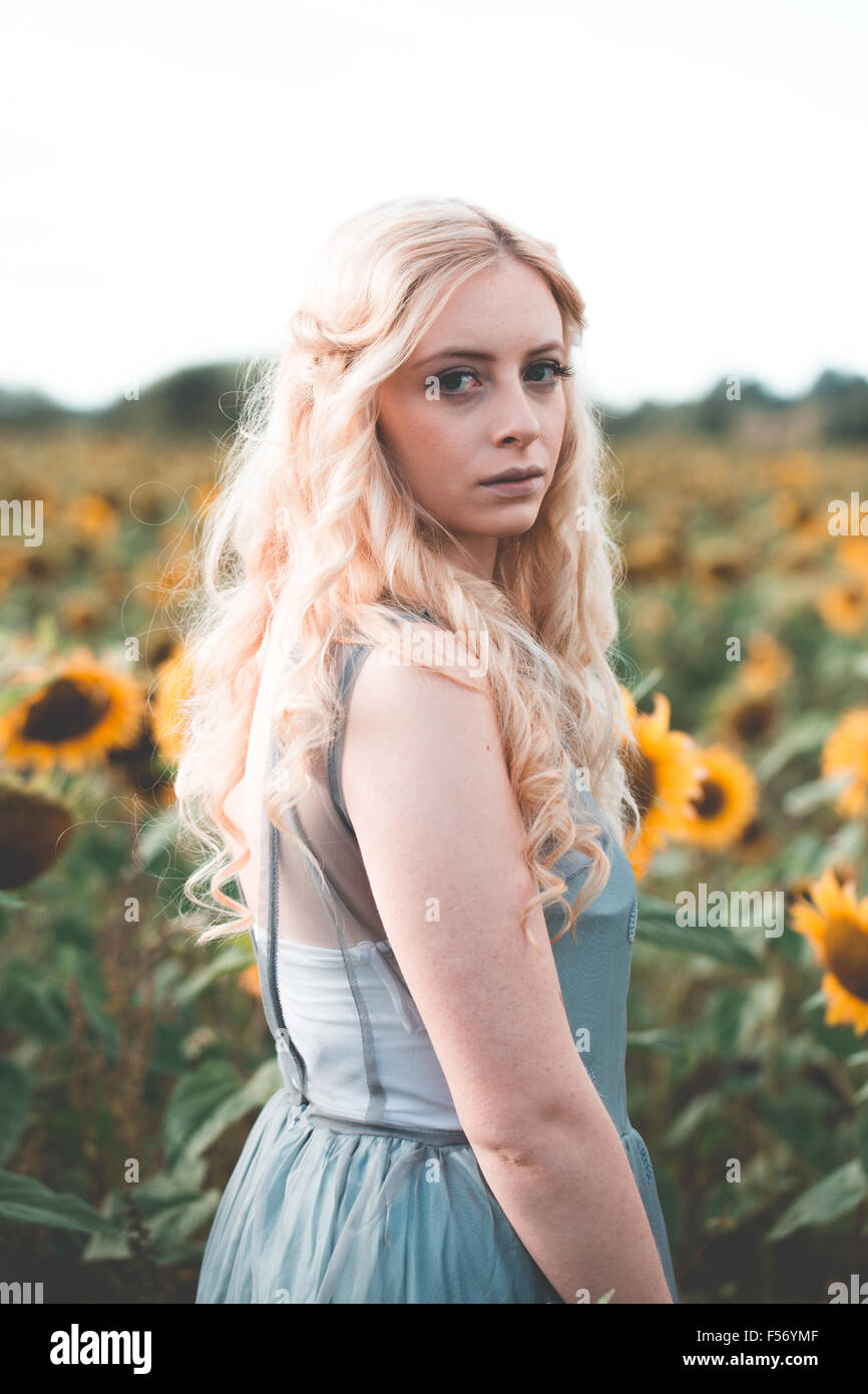Beautiful young woman in a sunflower field at golden hour Stock Photo ...