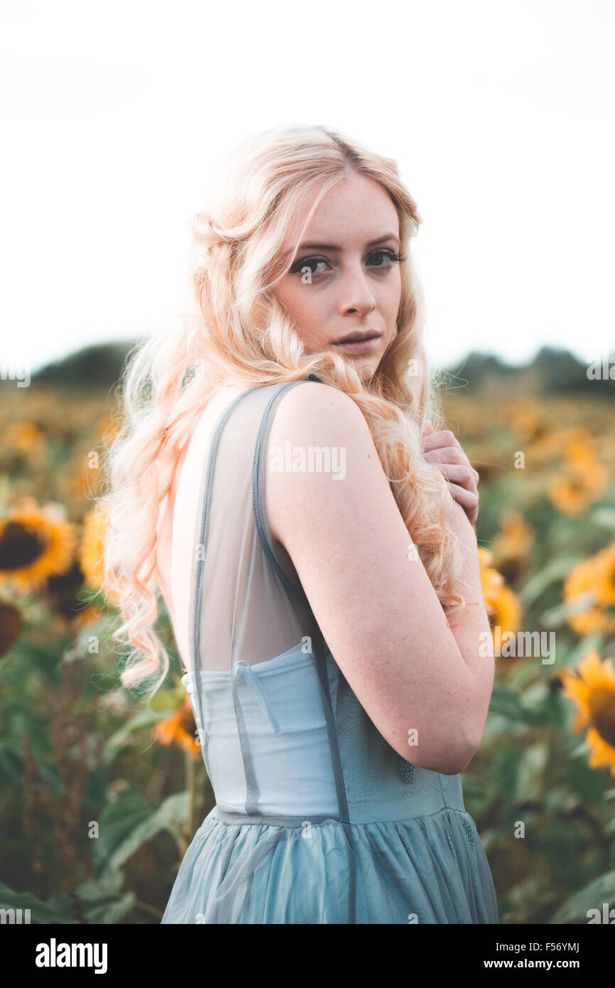 Beautiful young woman in a sunflower field at golden hour Stock Photo ...