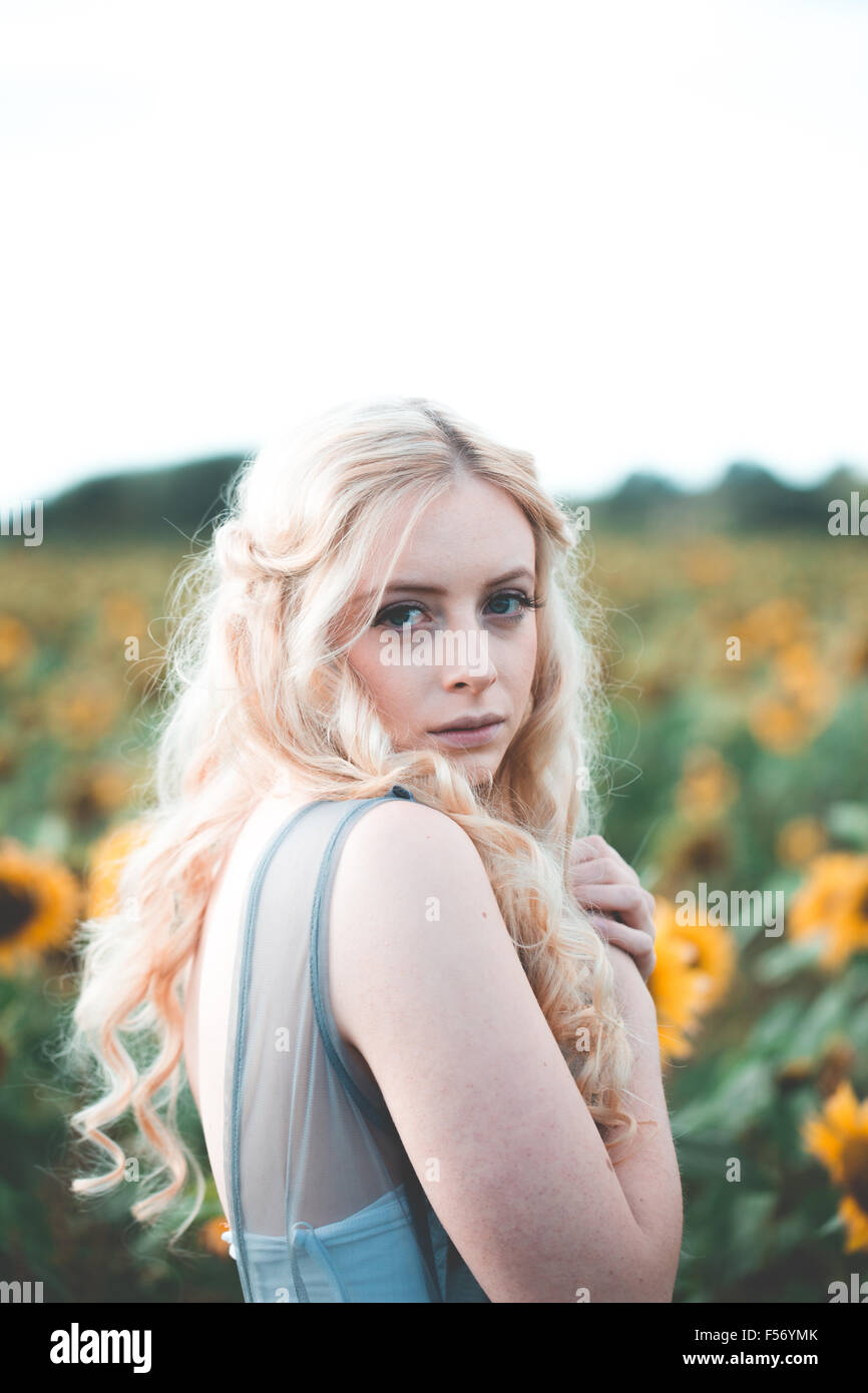 Beautiful young woman in a sunflower field at golden hour Stock Photo ...