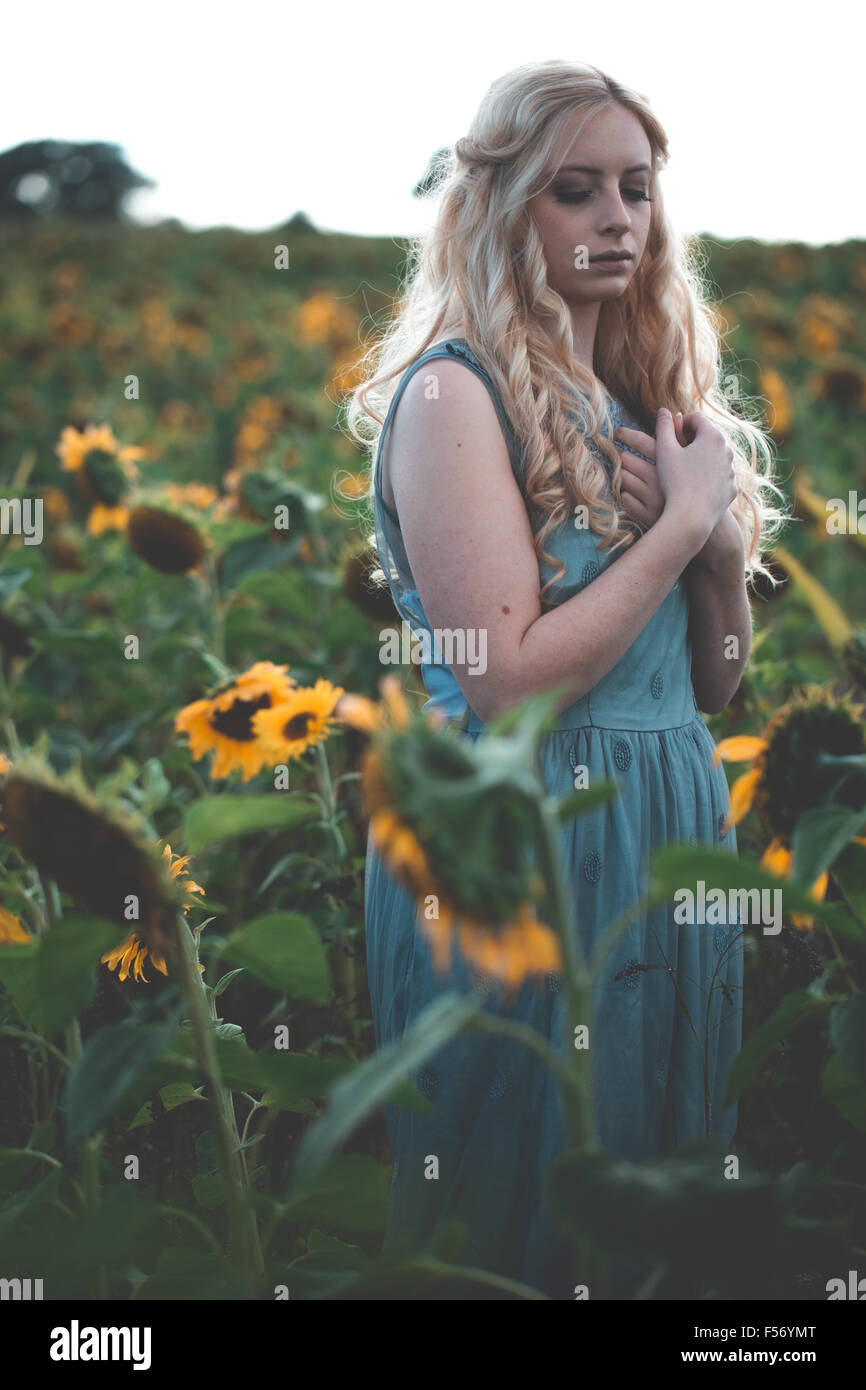 Beautiful young woman in a sunflower field at golden hour Stock Photo ...