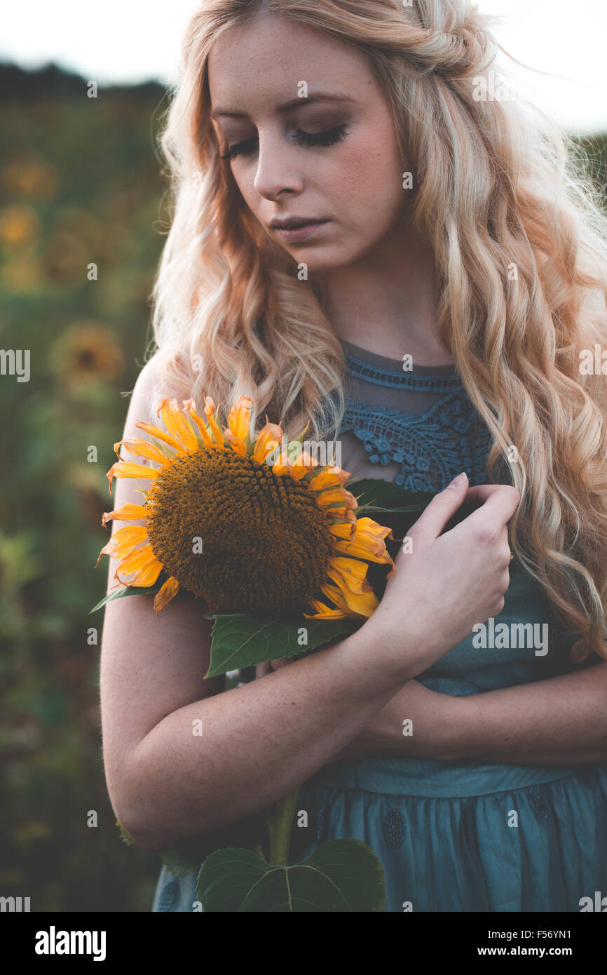 Beautiful young woman in a sunflower field at golden hour Stock Photo ...