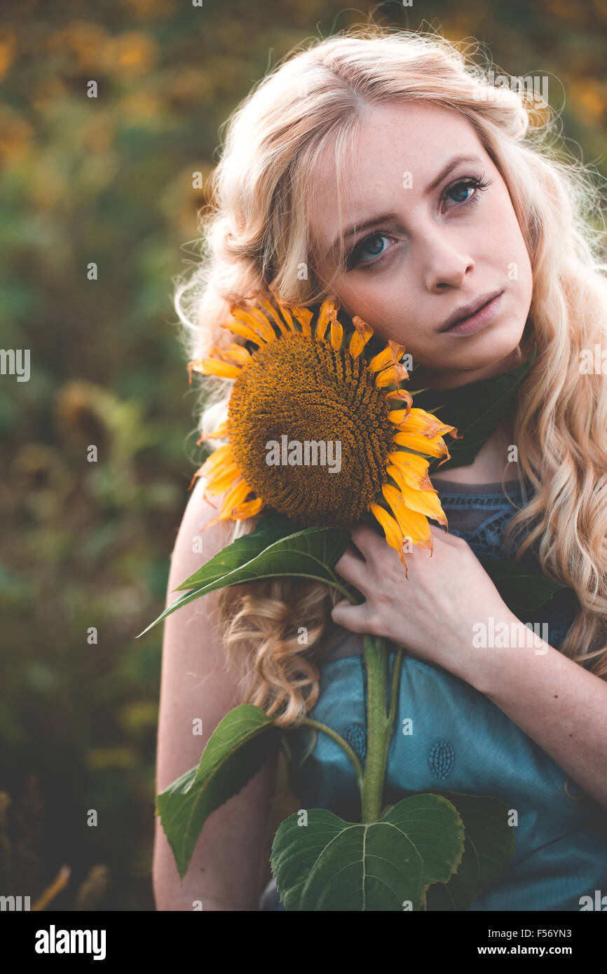 Beautiful young woman in a sunflower field at golden hour Stock Photo ...