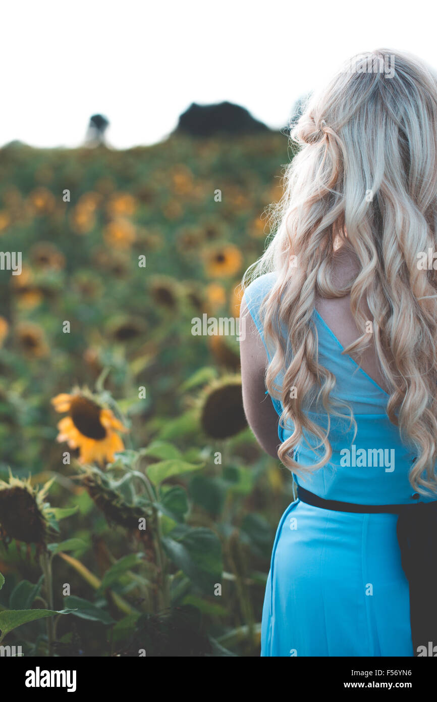 Beautiful young woman in a sunflower field at golden hour Stock Photo
