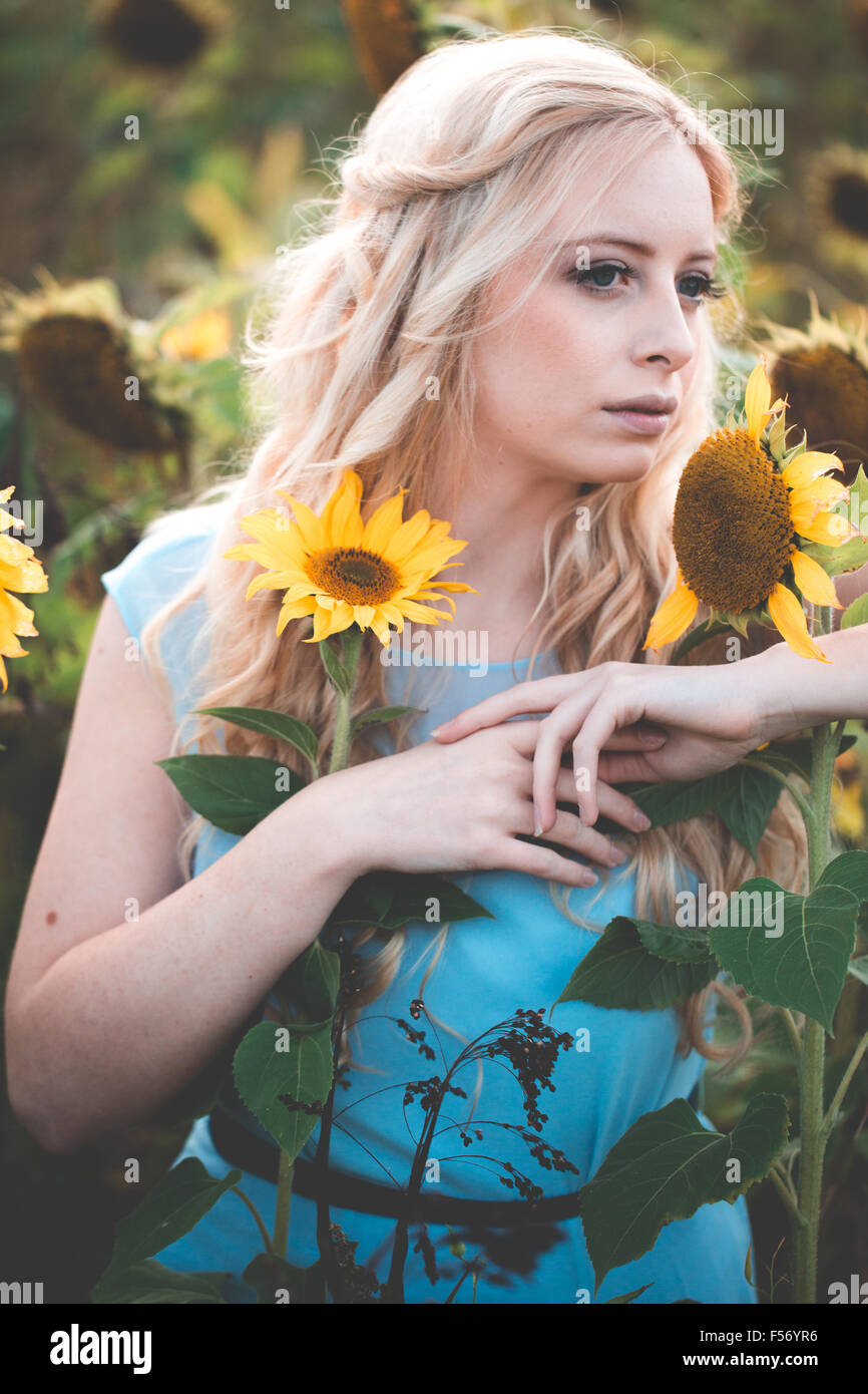 Beautiful young woman in a sunflower field at golden hour Stock Photo ...