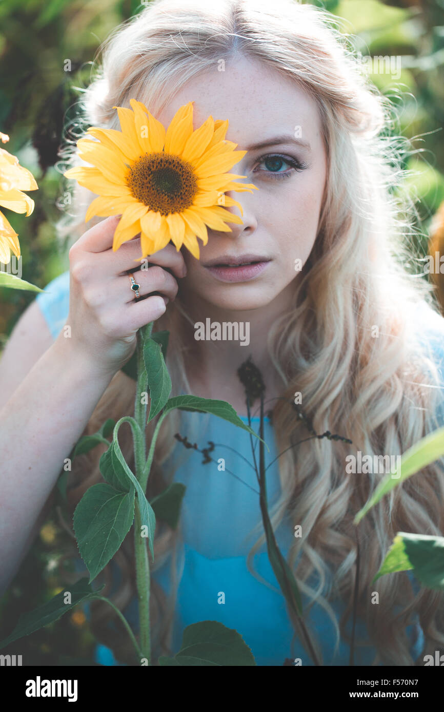 Beautiful young woman in a sunflower field at golden hour Stock Photo ...