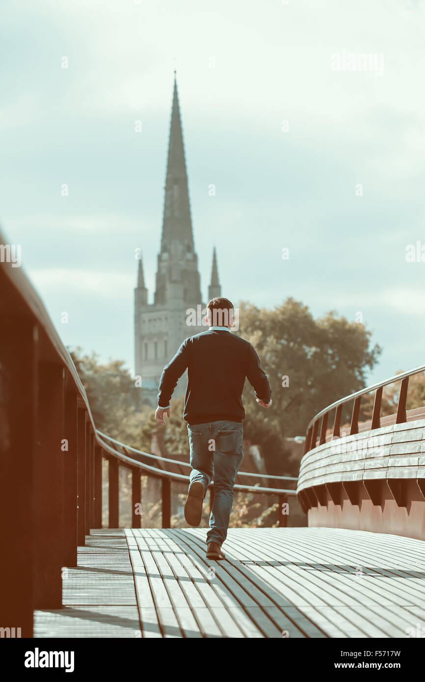 Man running across urban bridge with church in the background Stock Photo