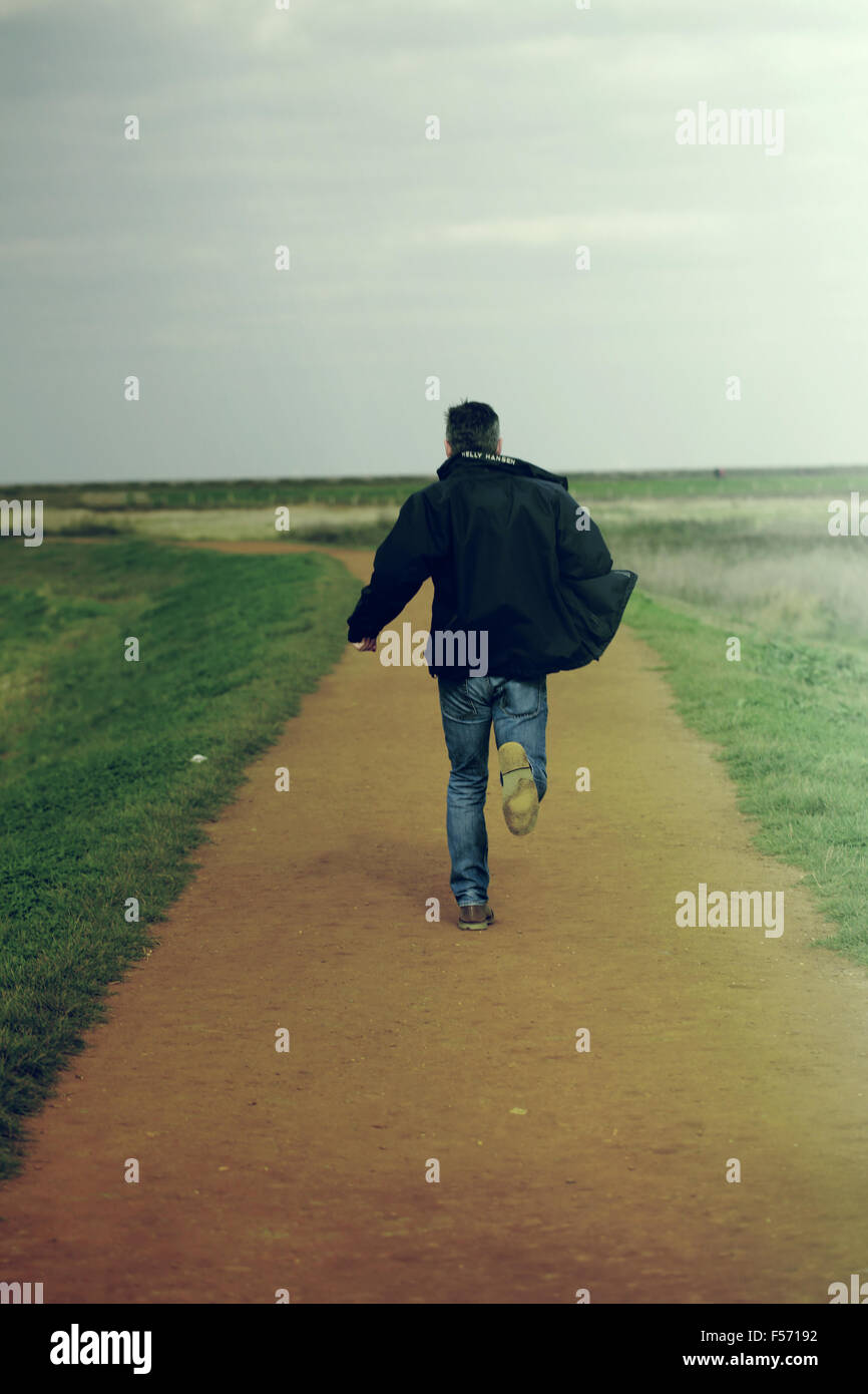 Middle aged man running in rural coastal area Stock Photo