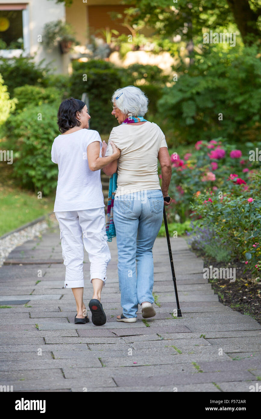 Elderly care at home, Nurse cares for an elderly woman, walking with walking aids, Stock Photo