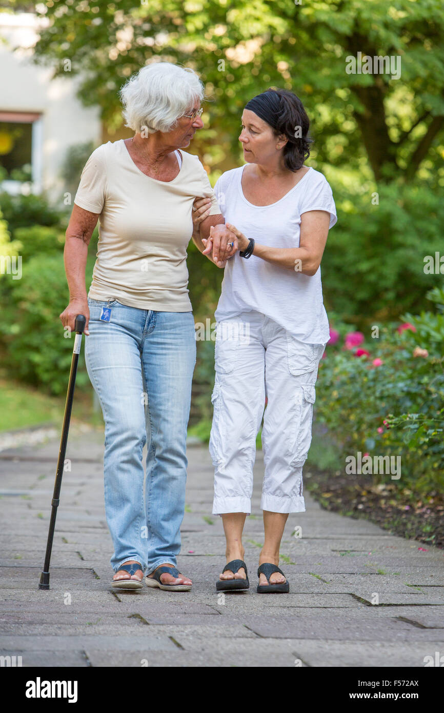 Elderly care at home, Nurse cares for an elderly woman, walking with walking aids, Stock Photo