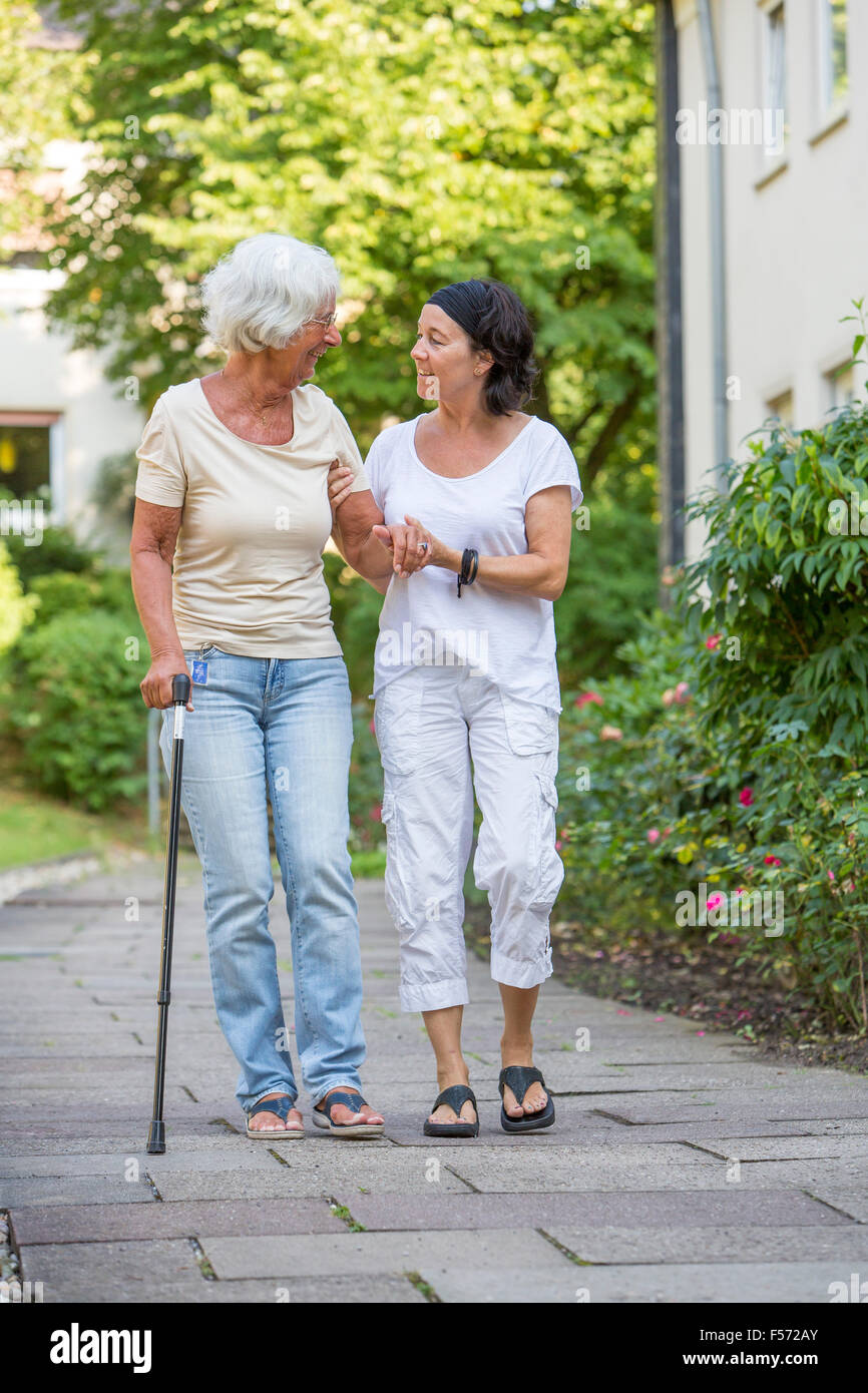 Elderly care at home, Nurse cares for an elderly woman, walking with walking aids, Stock Photo