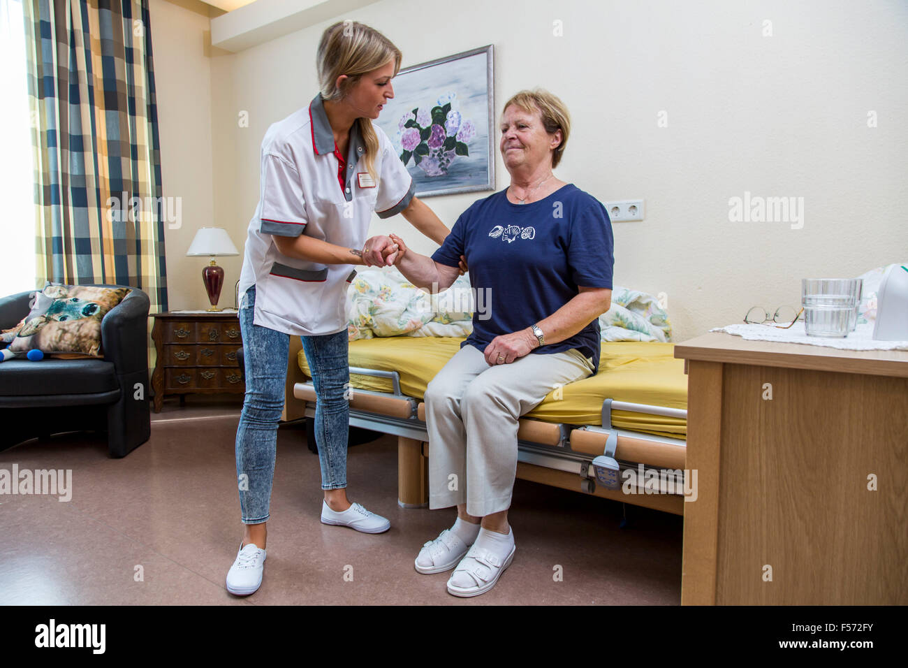 Elderly care in a nursing home, nurse helps an elderly woman getting