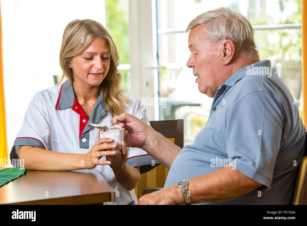 Elderly care in a nursing home, nurse helps an elderly man eating his