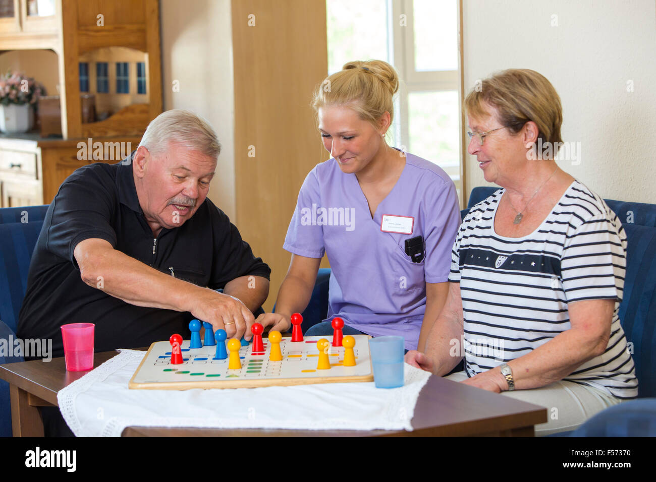 Elderly care in a nursing home, nurse plays with two patients a game, board game, entertainment, Stock Photo