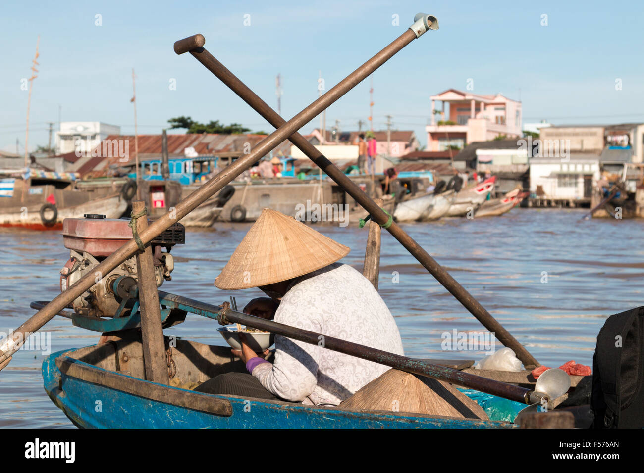 vietnamese boats and men women workers at Cai Rang floating markets to buy sell fresh fruit, food bowl of Vietnam. lady eats Pho Stock Photo