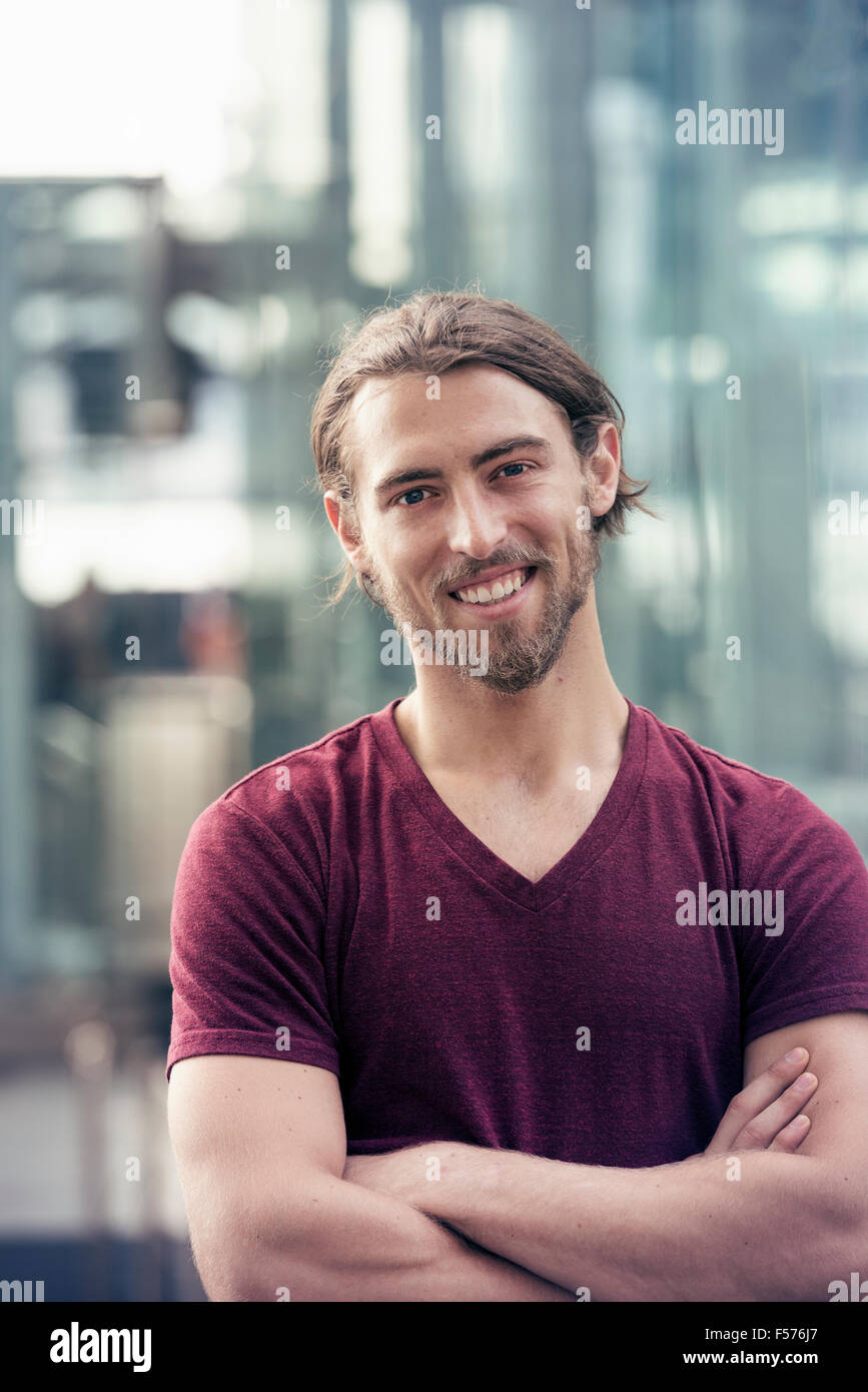 A young man in a city street, arms folded smiling Stock Photo