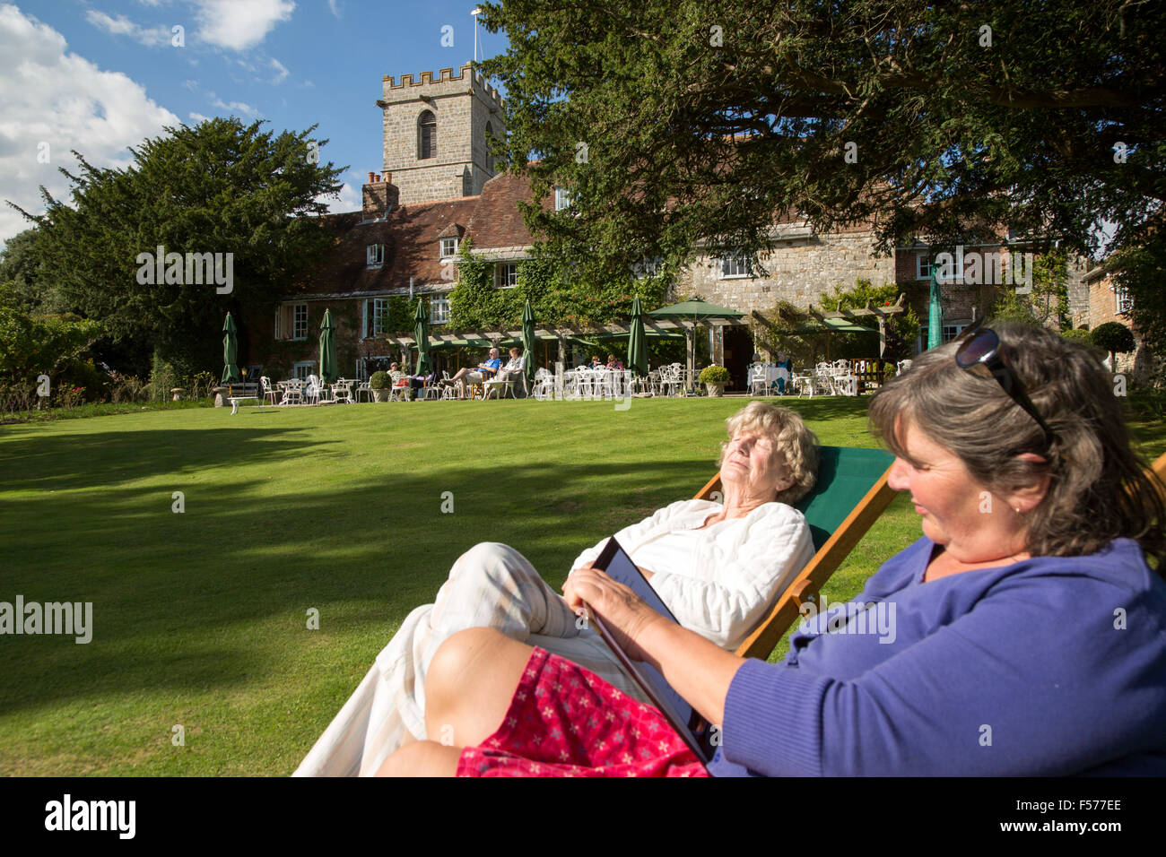 Two women sunbathing in gardens of the Priory Hotel, Wareham, Dorset, England, UK Stock Photo