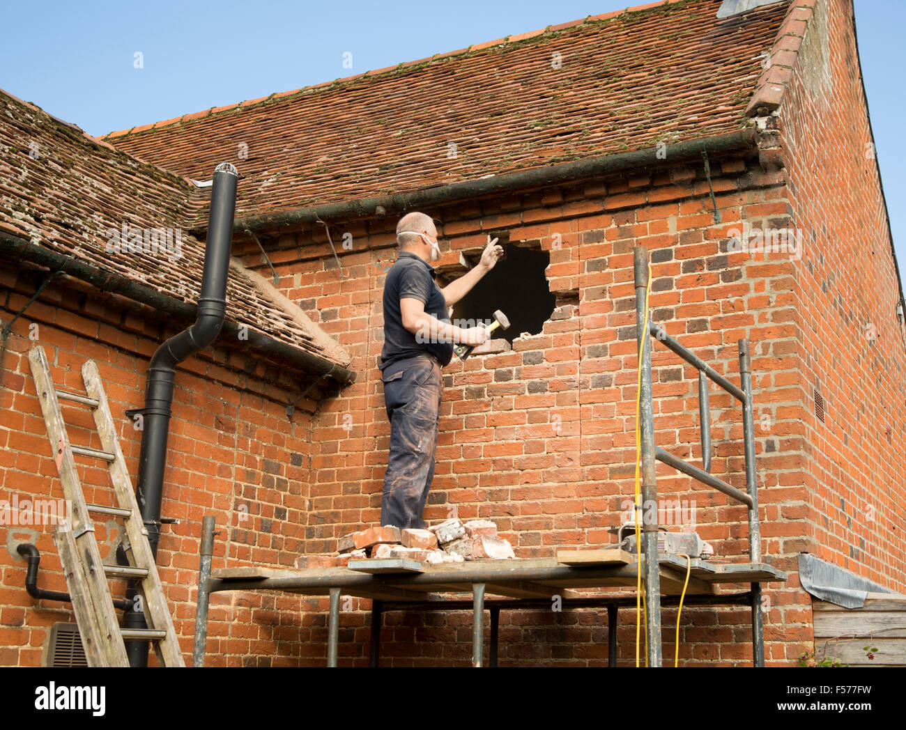 Builder removing red bricks to make window space, Suffolk, England, UK Stock Photo